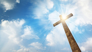 a wooden christian cross with bright sun and