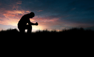 man praying in the grassy