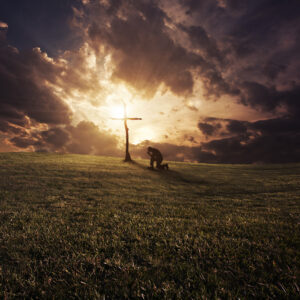 a man kneeling at a cross at sunset rXUS30WlR