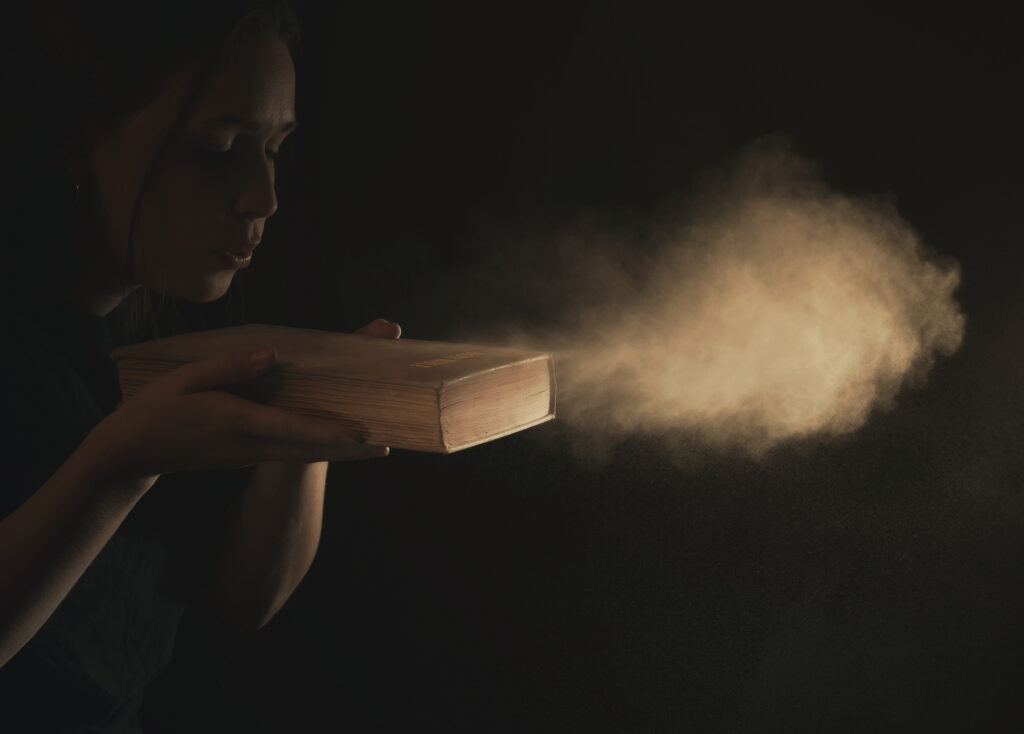 blowing the dust off the cover of an old bible BXE2jAWeR