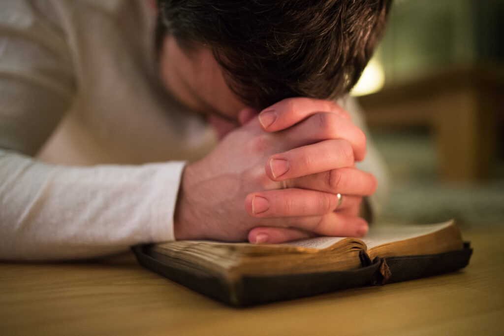How to Use Scripture in Worship Music for a More Meaningful Experience 2 graphicstock unrecognizable young man praying kneeling on the floor hands on his bible close up HdxIWadLz