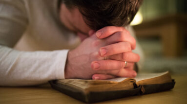 graphicstock unrecognizable young man praying kneeling on the floor hands on his bible close up HdxIWadLz