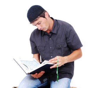 muslim man is holding holly book qoran and praying on traditional way SYpErRaSj