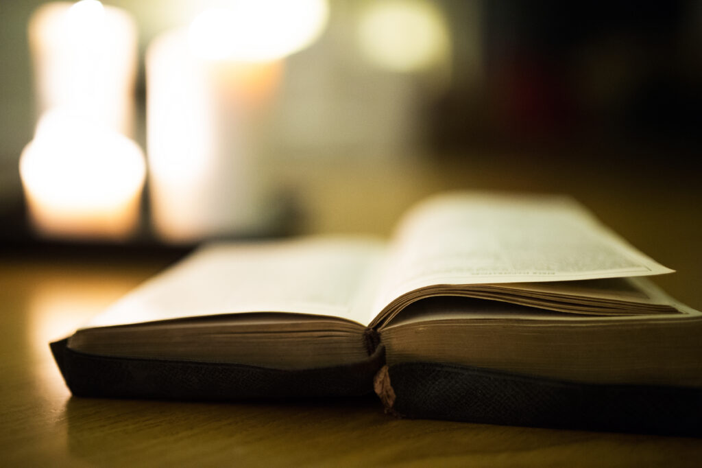 graphicstock close up of an old bible laid on wooden floor burning candles in the background H x53hu8Mb