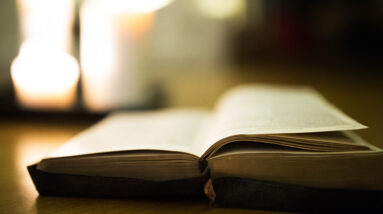 graphicstock close up of an old bible laid on wooden floor burning candles in the background H x53hu8Mb 2