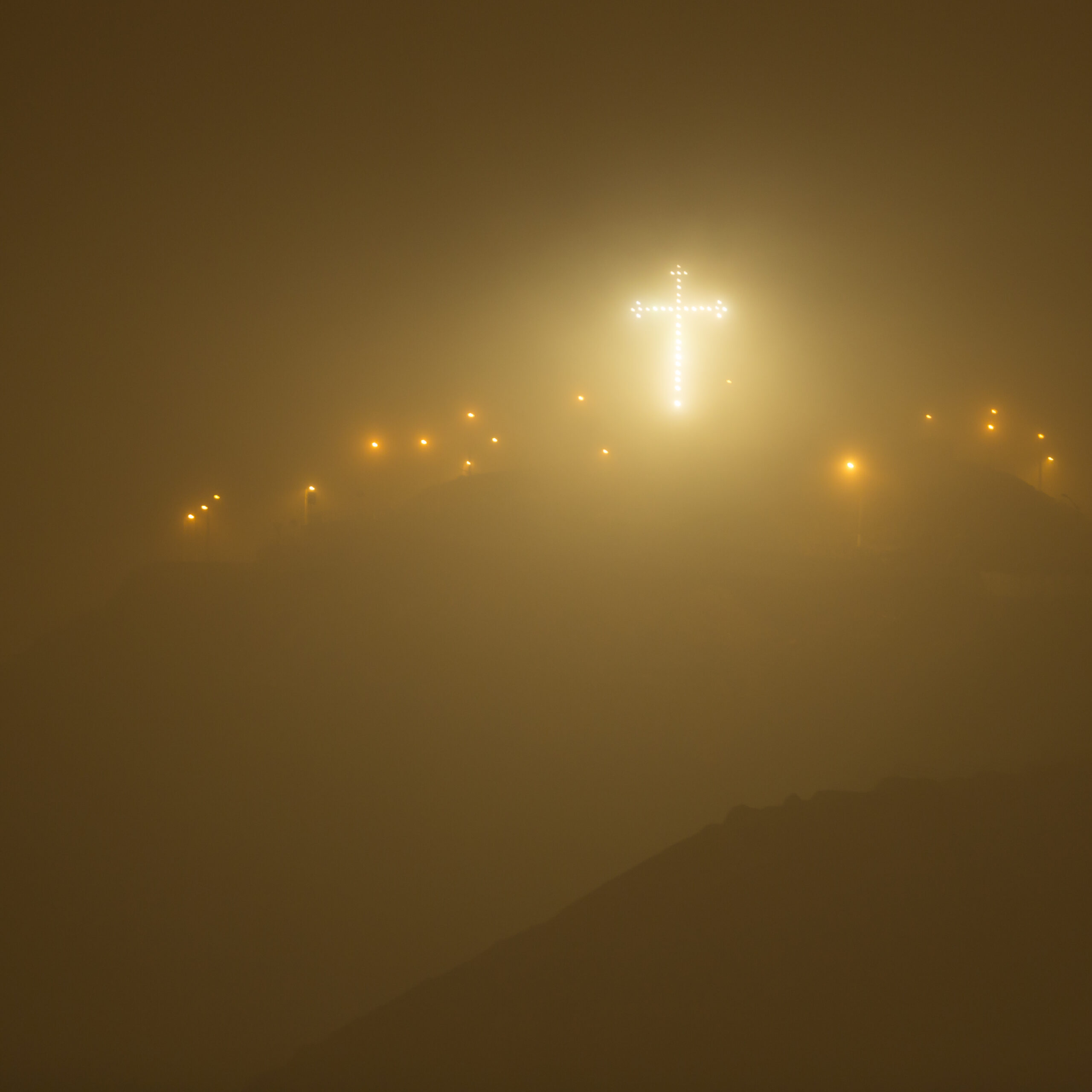 illuminated cross on a hill at night scaled