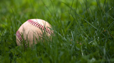 one aged and worn hardball or baseball laying in the green grass BYMUpwArs