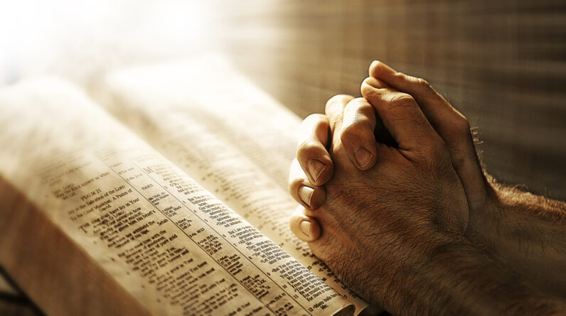two hands are in prayer while resting on the bible BQIrlkzlR