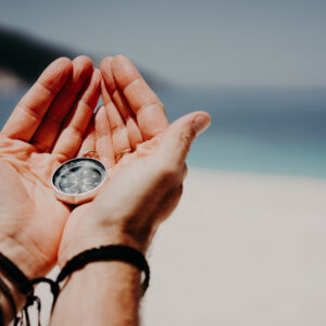 storyblocks mans hand holding compass against the backdrop of beach and sea the concept of travel summer vacation holiday and journey BHMpPQhp14