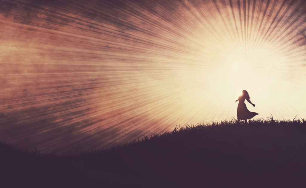 woman standing in praise on a grassy hill HsBeHhKIPx