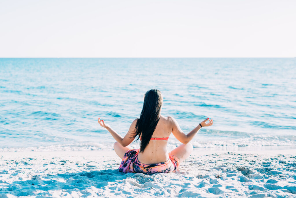 graphicstock back view of young beautiful woman doing yoga at the beach in summertime in lotus position relax meditation spiritually concept B6lwosmq1Z