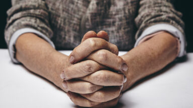 studio photography of praying hands of a senior woman on table old hands clasped on a table Hpl8MwLNYe