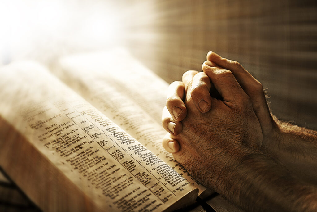 two hands are in prayer while resting on the bible BQIrlkzlR