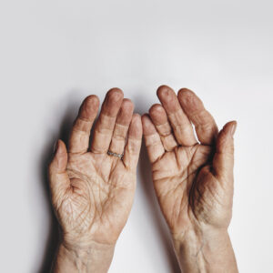 top view of two empty female hands over grey background senior woman hands pleading wrinkled palms of aged woman with copy space STW ePUEKx